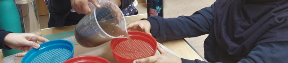 A child pouring murky water through a sieve.